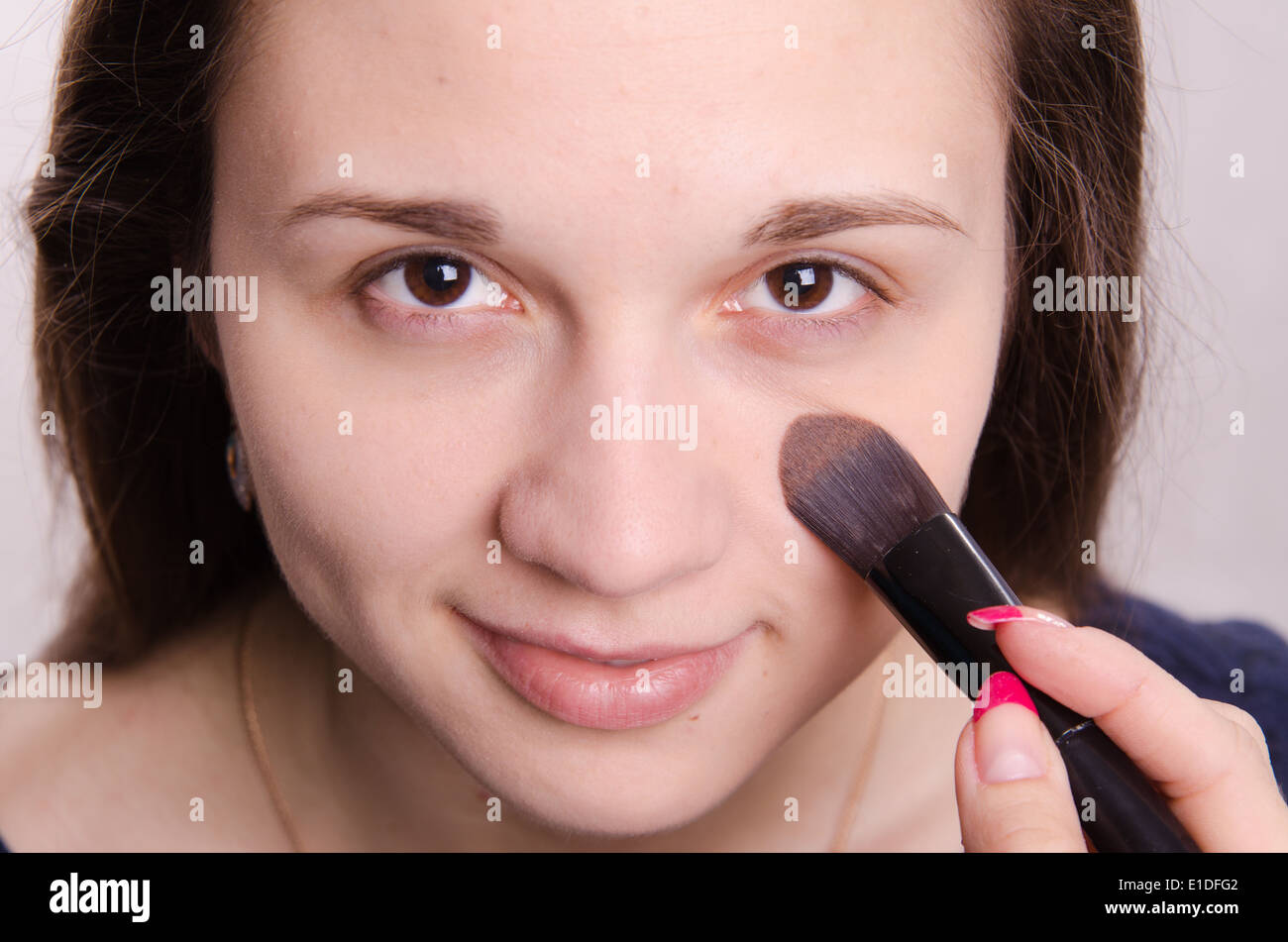 Makeup artist applies foundation of a beautiful young girl in the