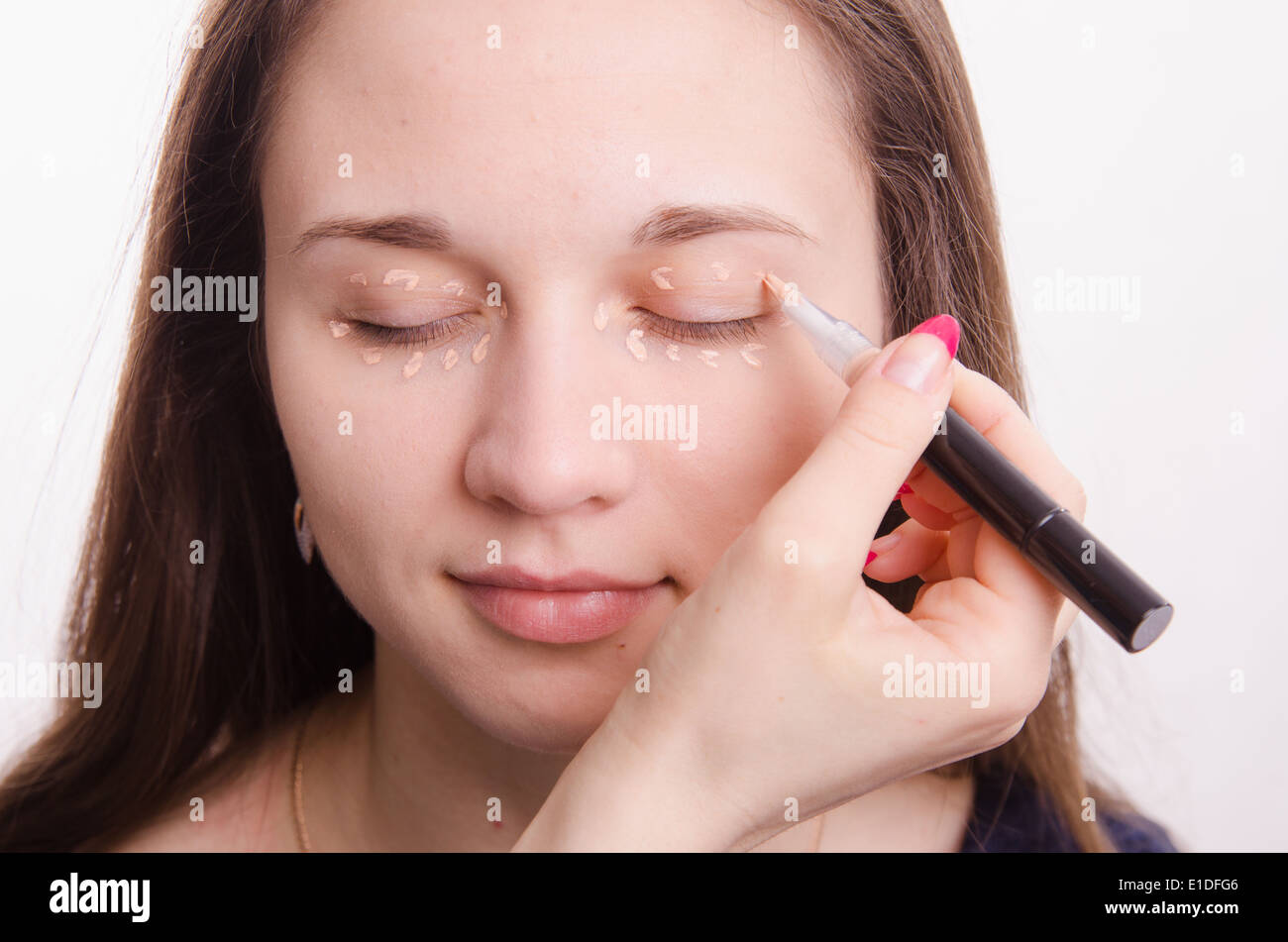 Makeup artist applies foundation of a beautiful young girl in the