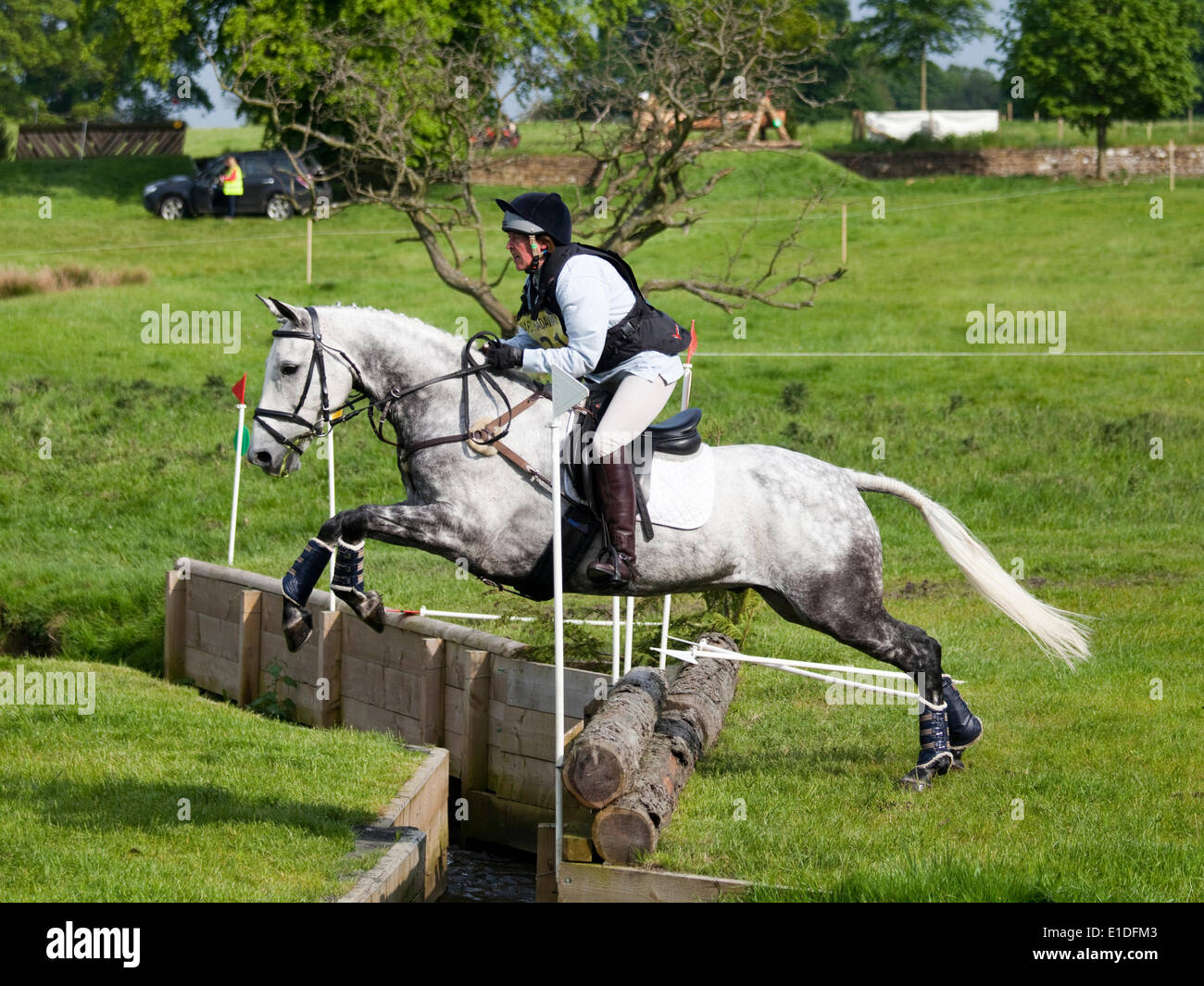 Belsay, England - May 31, 2014: A competitor in the cross country section clears the open ditch during the 2014 Belsay Horse Trials, held for the second year running in the grounds of Belsay Castle in Northumberland, England. Belsay Castle is managed by English Heritage and is open to the public all year. Stock Photo