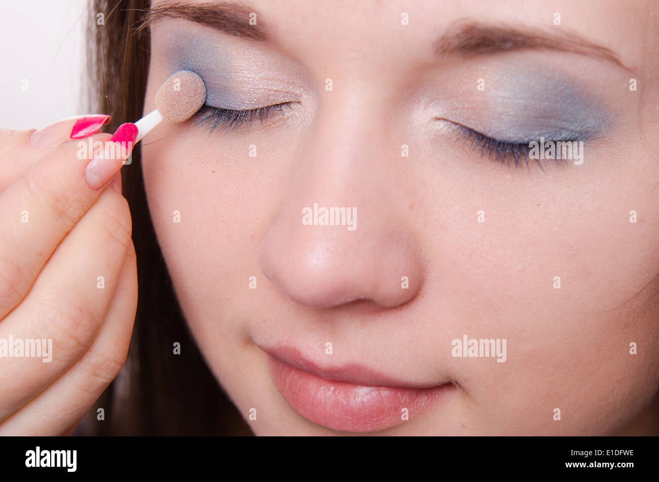 Makeup artist paints the eyelids of a beautiful young girl in the