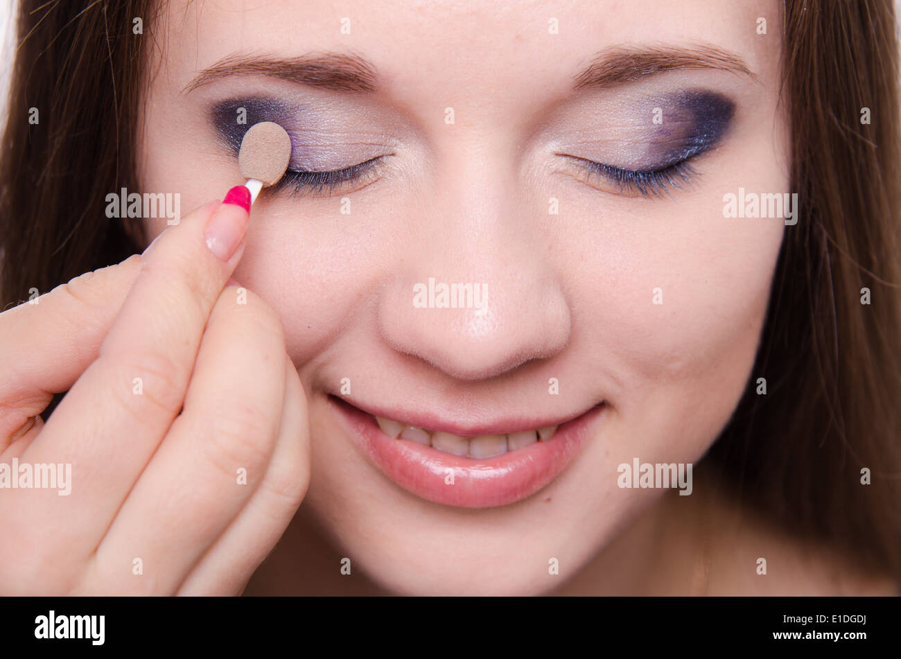 Makeup artist paints the eyelids of a beautiful young girl in the