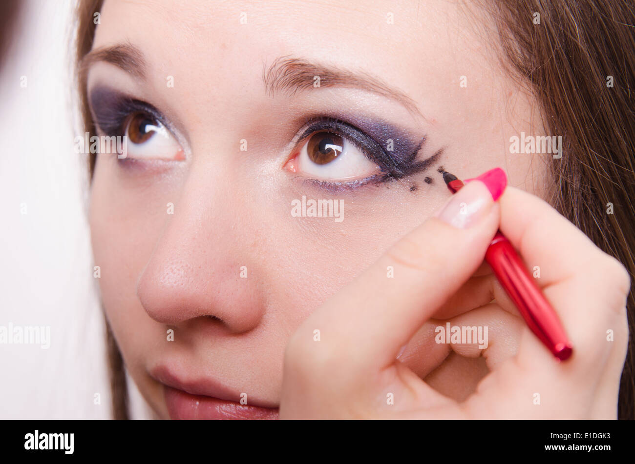 Makeup artist draws arrows beautiful young girl in the makeup Stock