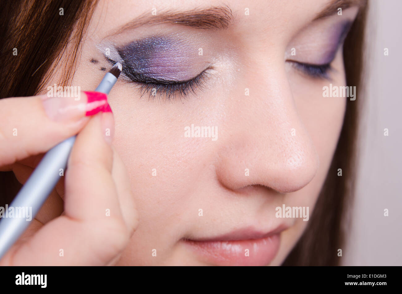 Makeup artist draws arrows beautiful young girl in the makeup Stock