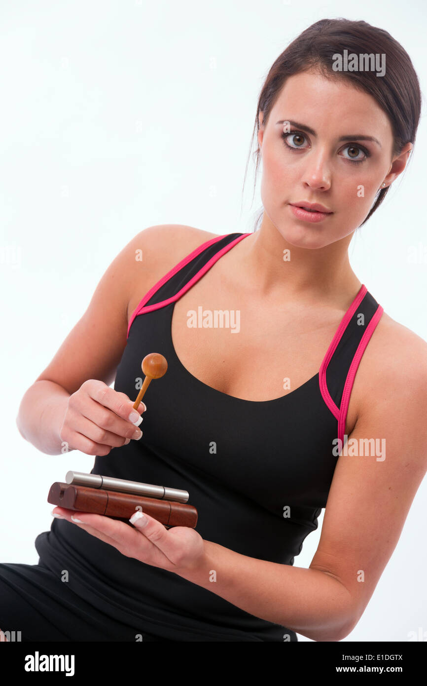 Attractive woman striking chime to bring an end to her meditation session Stock Photo