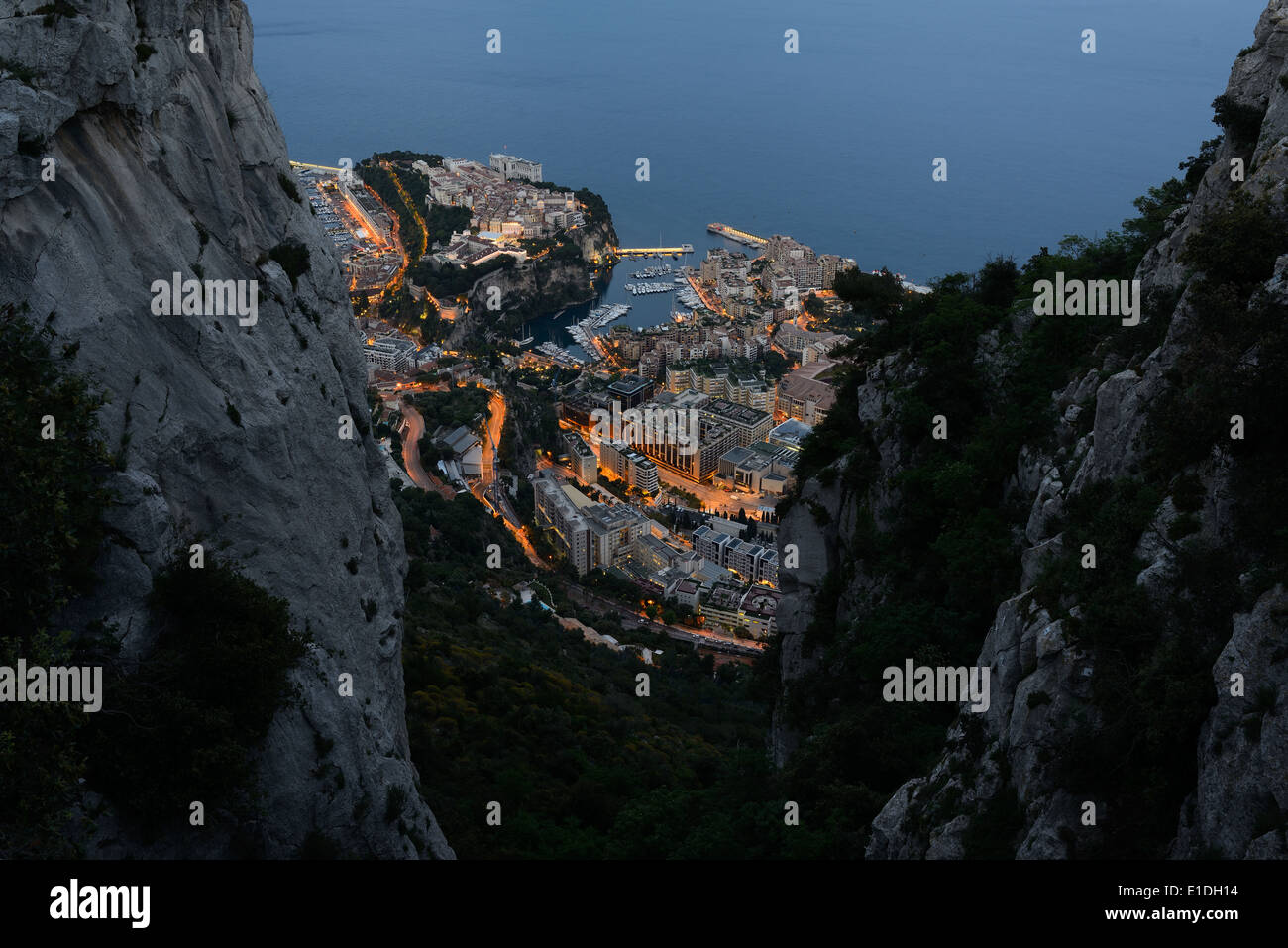 The ward of Monaco-Ville aka 'le Rocher' and the marina of Fontvieille framed between two limestone cliffs at dusk. Principality of Monaco. Stock Photo