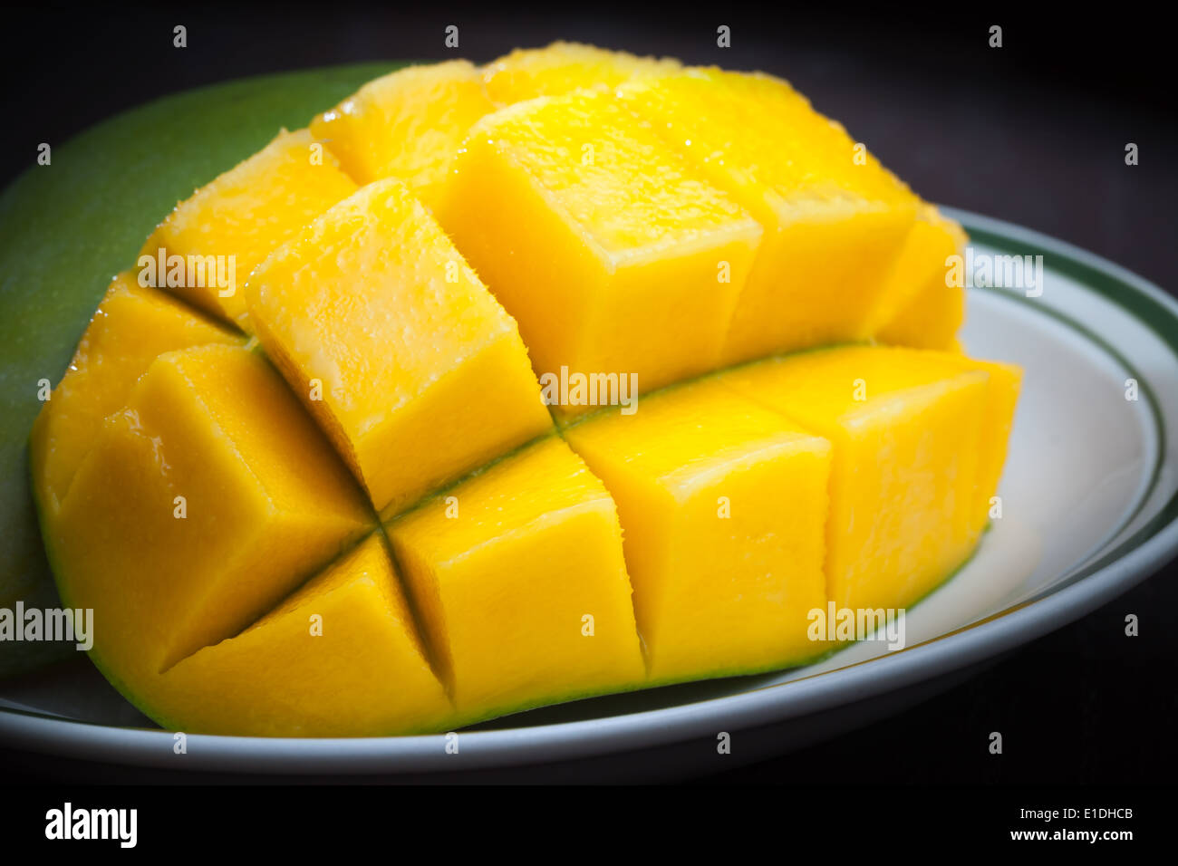 Macro photo of yellow sliced mango on white plate Stock Photo