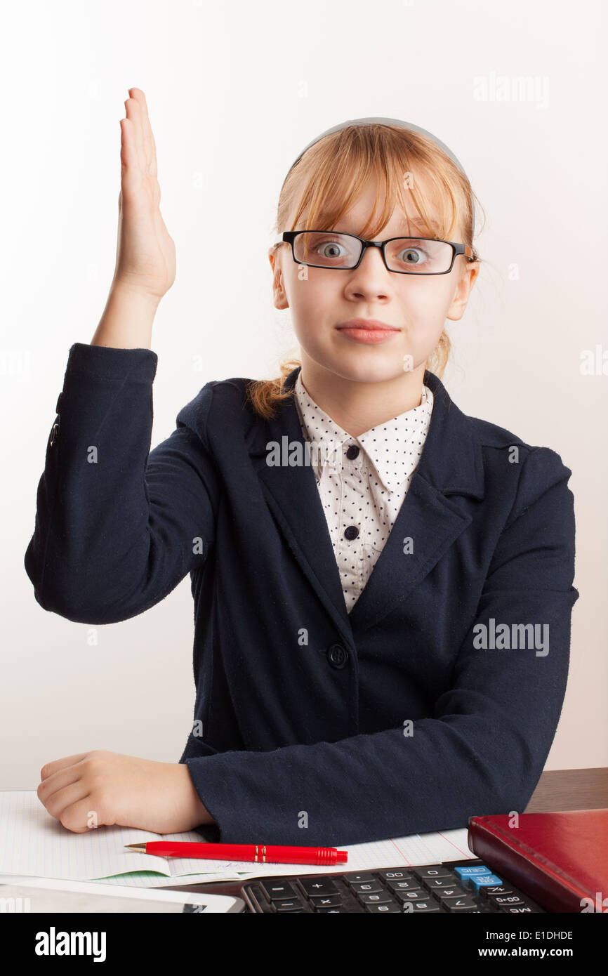 Little blond schoolgirl with glasses raises her hand Stock Photo
