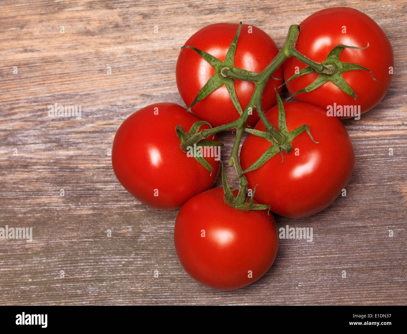 Tomatoes on the vine on rustic wooden table background Stock Photo