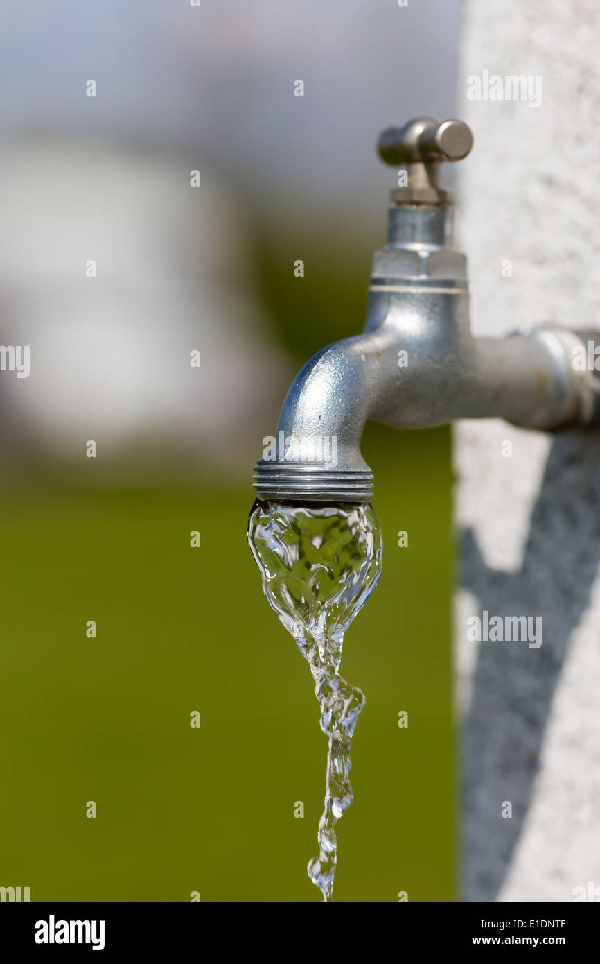 Water flowing from outdoors water tap on a sunny day. Stock Photo