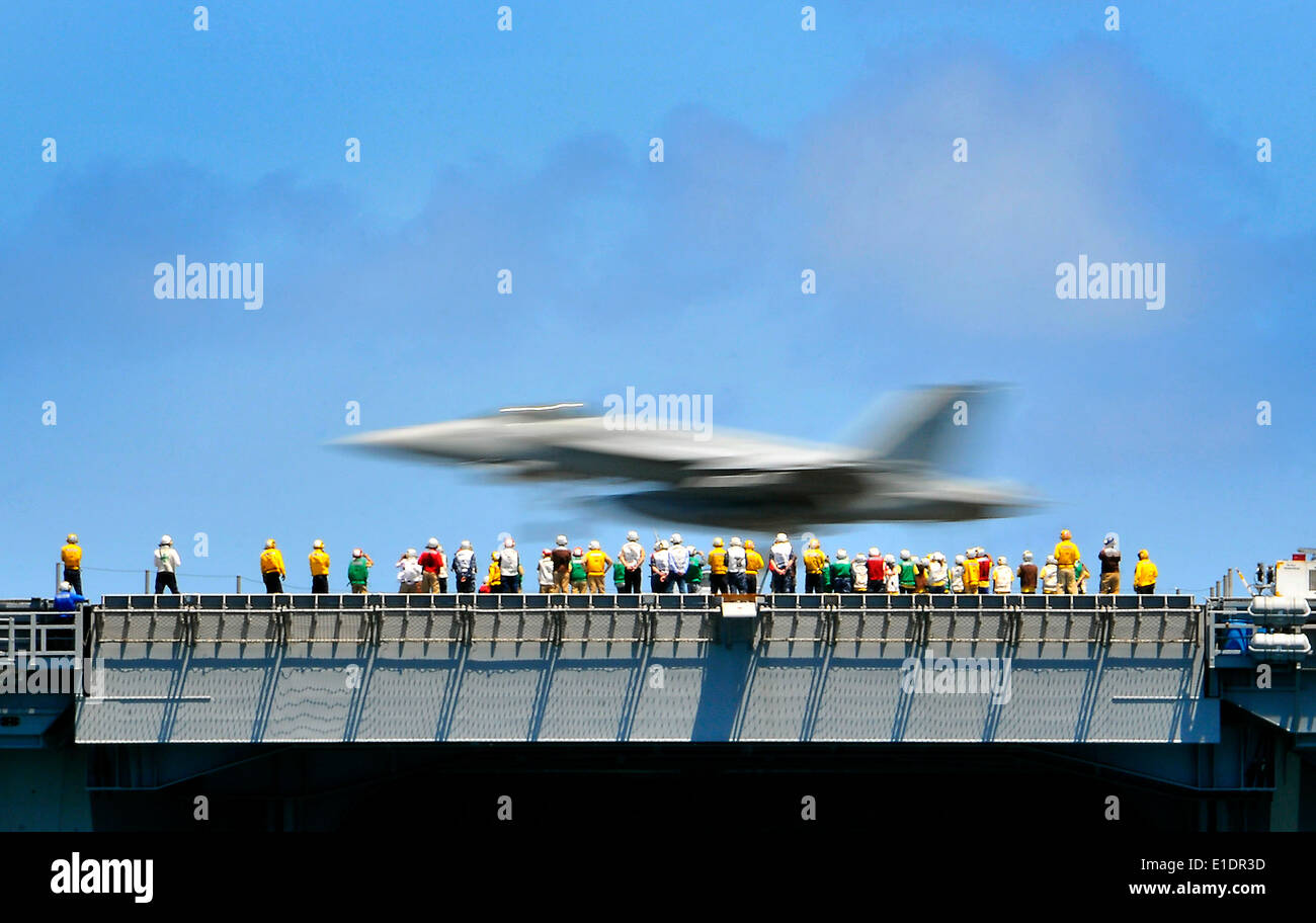 U.S. Sailors observe an FA/18E Super Hornet aircraft assigned to the ?Sunliners? of Strike Fighter Squadron 81 as it makes an a Stock Photo