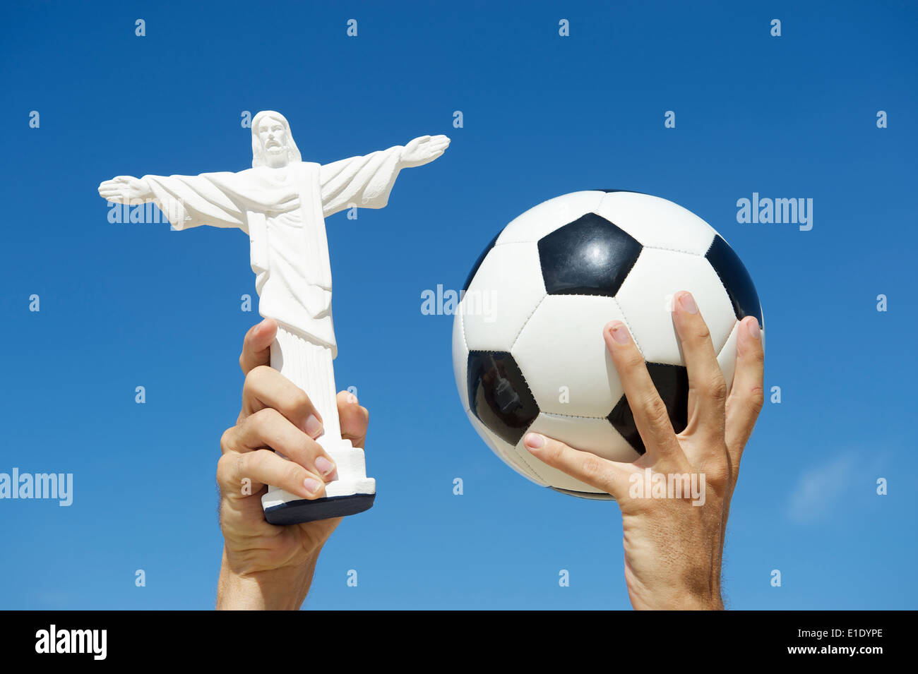 Brazilian hands holding football soccer ball and souvenir statue of Corcovado Cristo Redentor in the air bright blue sky Stock Photo
