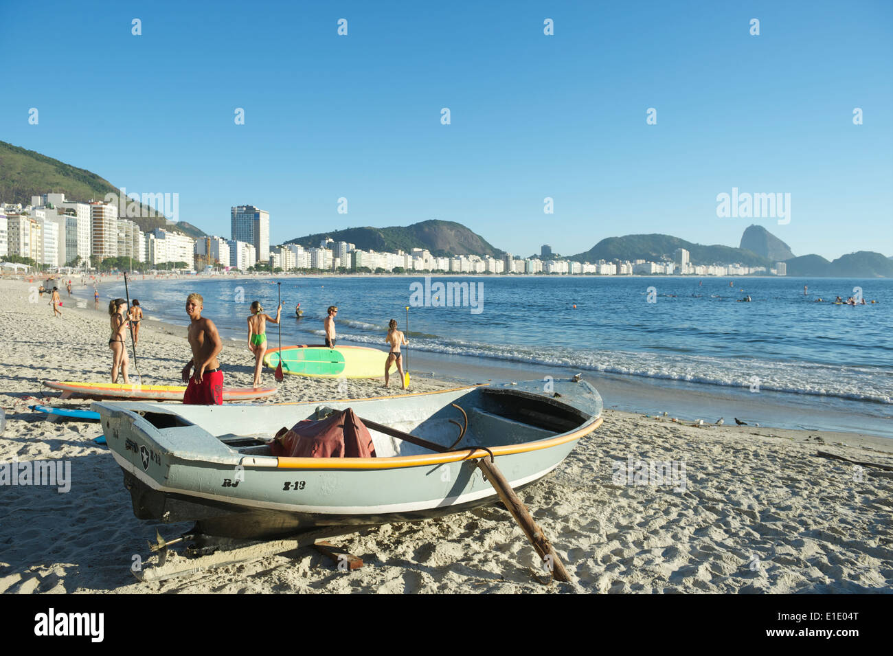 RIO DE JANEIRO, BRAZIL - FEBRUARY 04, 2014: A Brazilian fishing boat sits next to stand up paddlers. Stock Photo