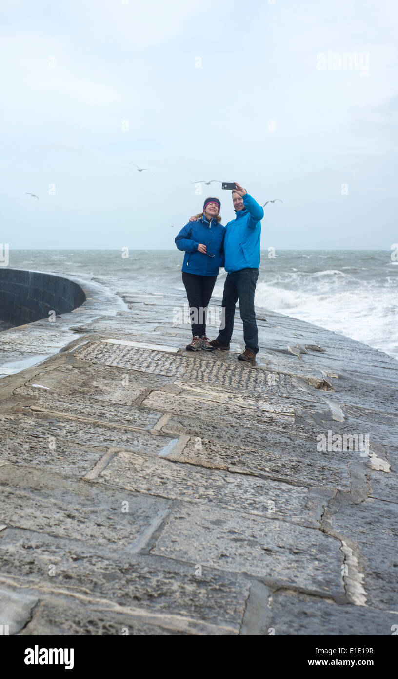 Couple taking a selfie on the Cobb, Lyme Regis, Dorset, England, UK Stock Photo