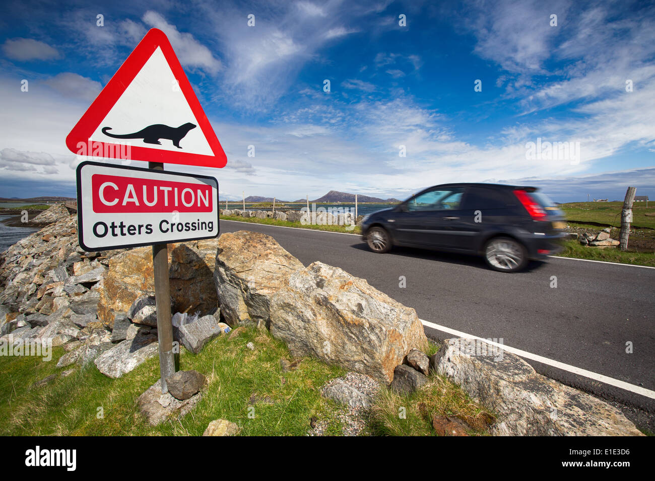 Caution Otters crossing road sign with vehicle driving past. Outer Hebrides, Scotland, UK Stock Photo