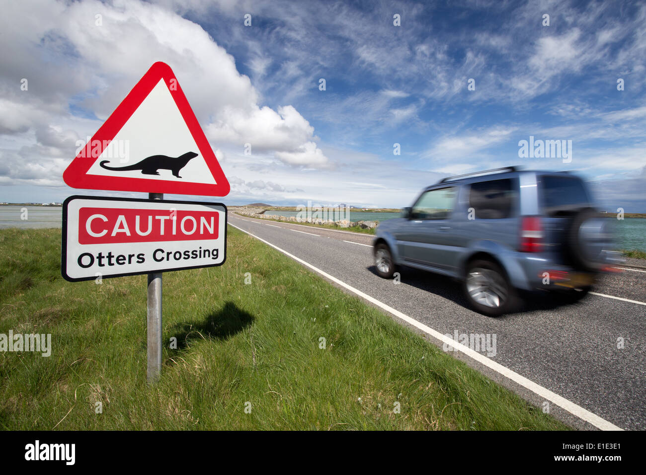 Caution Otters crossing road sign with vehicle driving past. Outer Hebrides, Scotland, UK Stock Photo