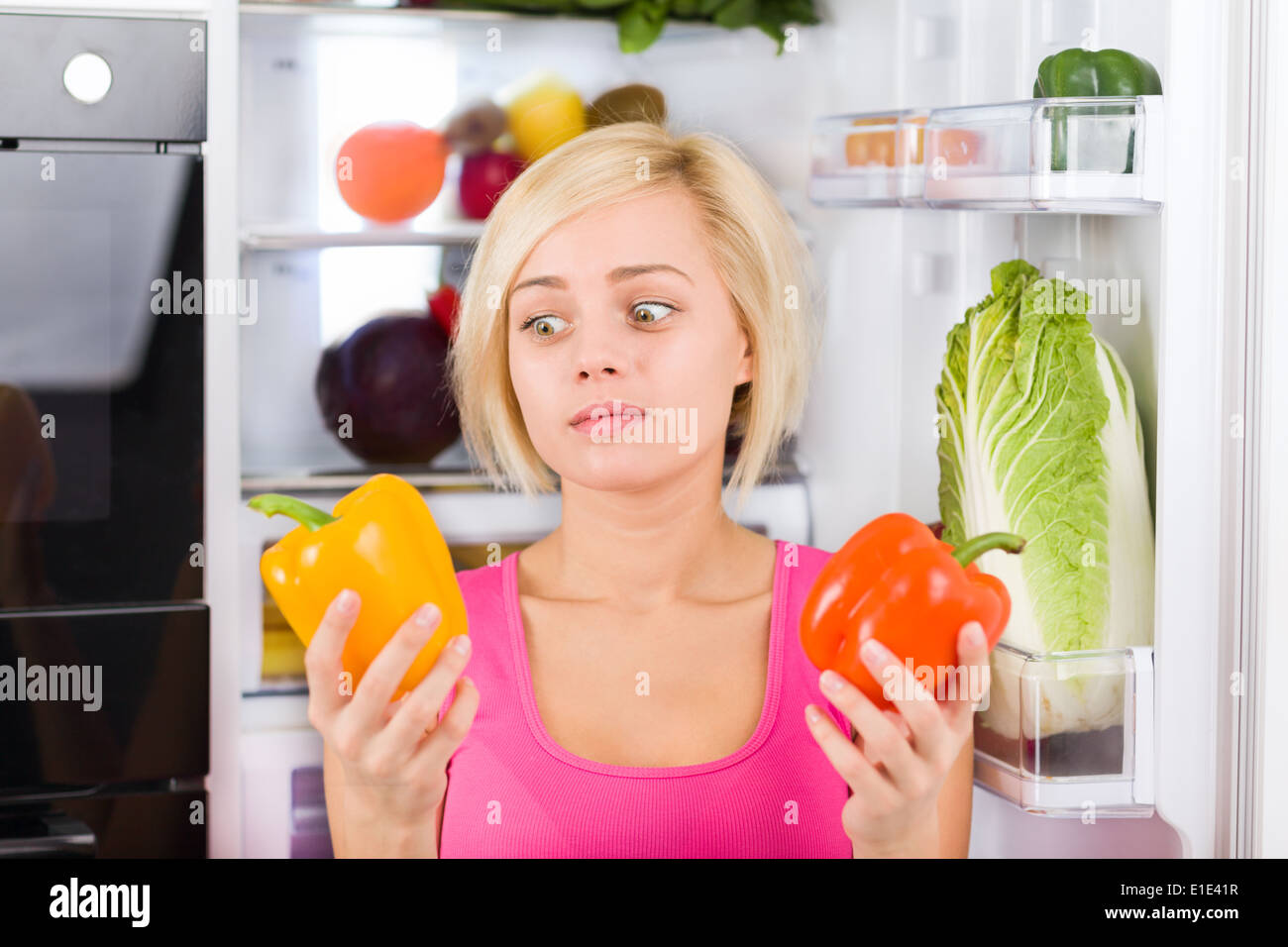 girl unhappy look red pepper, refrigerator Stock Photo Alamy