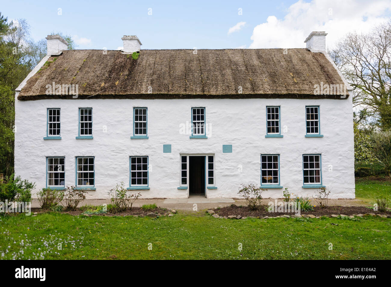 A very large Irish farmhouse with whitewashed walls and a thatched roof