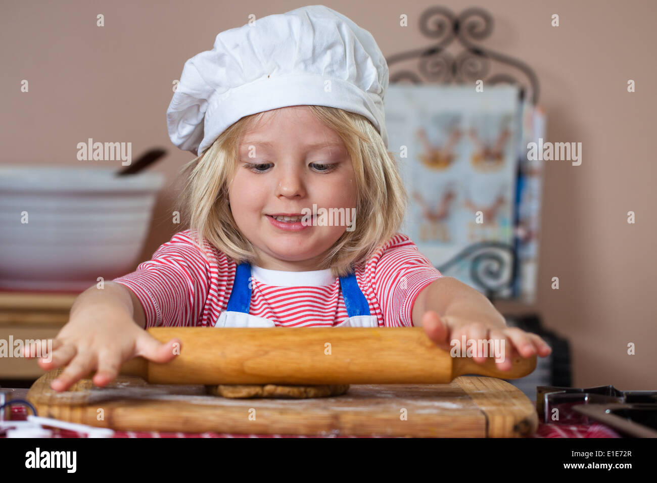 A cute young boy is baking and rolling out a gingerbread dough Stock Photo
