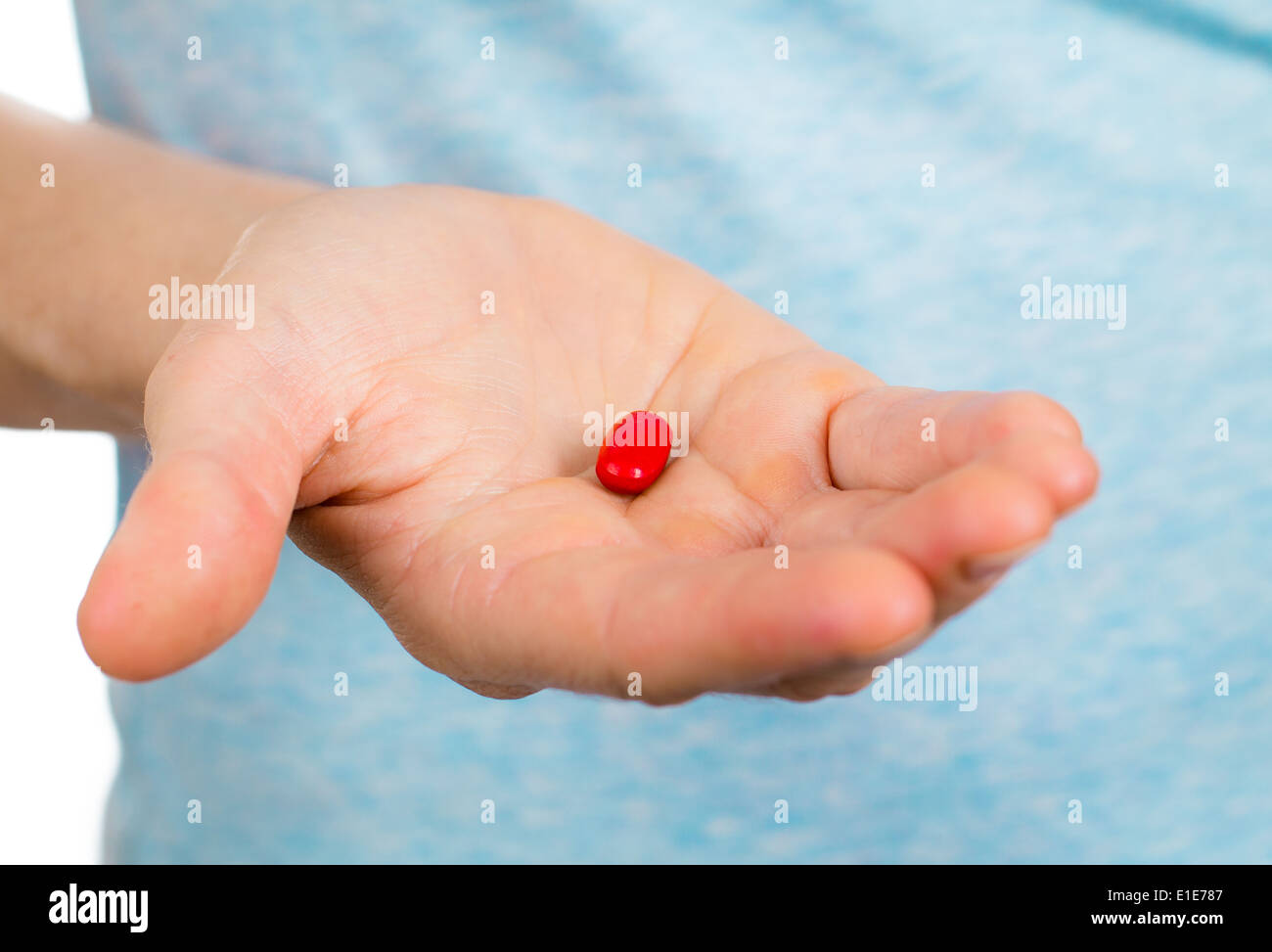 Close-up shot of a hand holding a red pill. Stock Photo