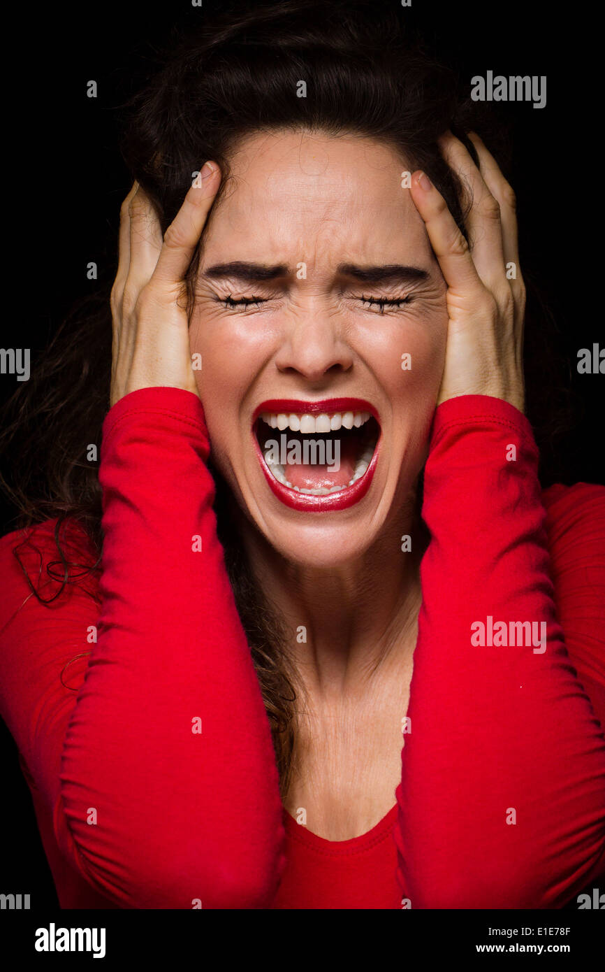 A strong dark image of a very upset, angry and emotional woman screaming. Stock Photo