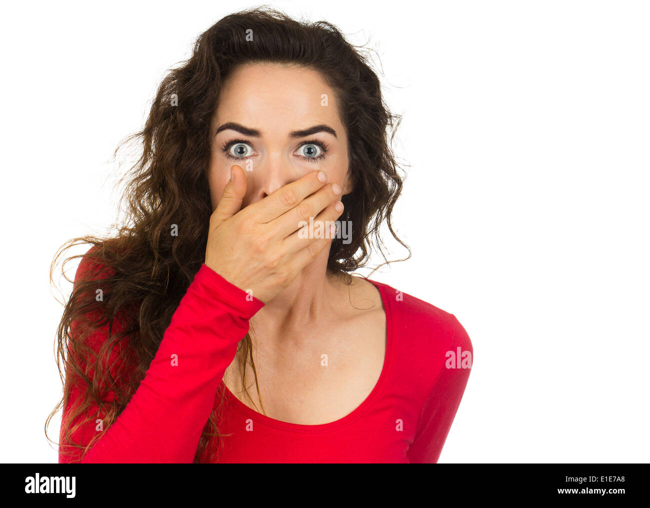 A shocked and frightened woman covering her mouth in surprise and disbelief. Isolated on white. Stock Photo
