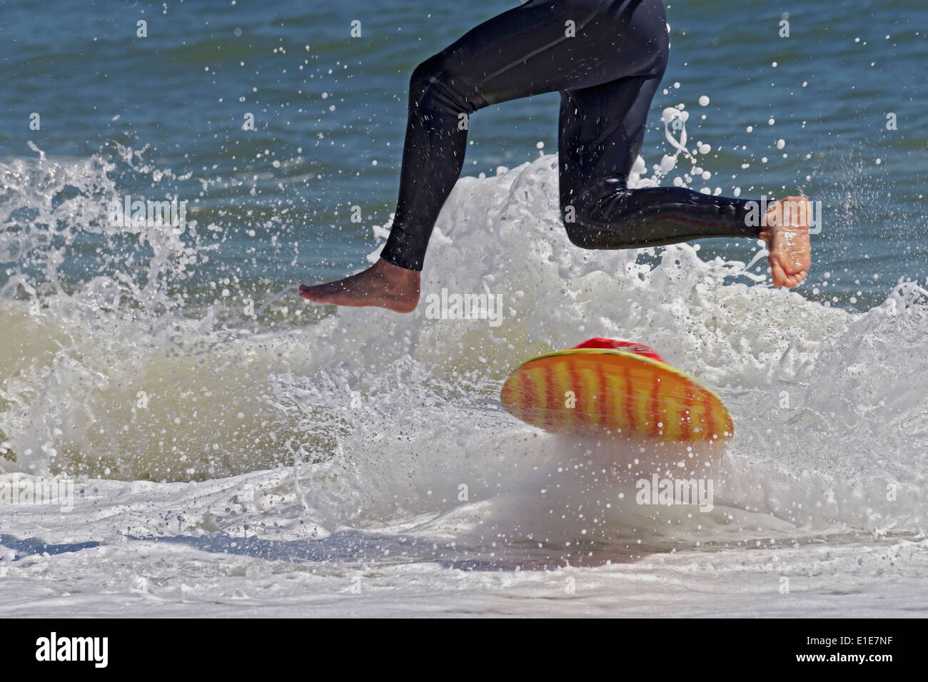 Skimboarder Wearing Wetsuit Jumping Into Wave Stock Photo