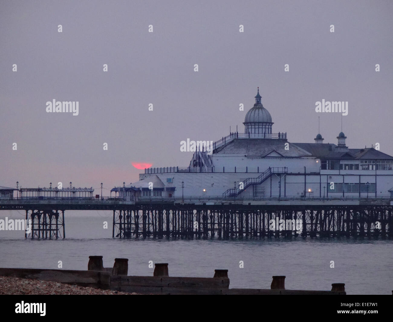 Eastbourne, East Sussex, UK. 2 June 2014. Very brief glimpse of the sun as it rises into low coud behind the pier. According to some forecasts, the weather is expected to turn wetter over the next fortnight Stock Photo