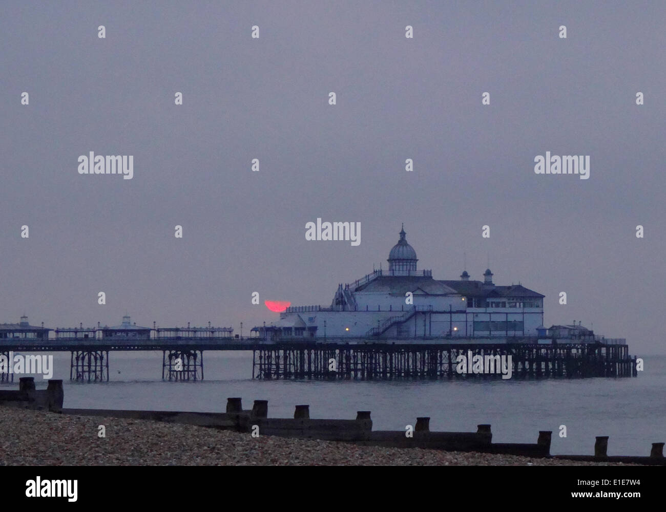Eastbourne, East Sussex, UK. 2 June 2014. Brief glimpse of the sun as it rises into low coud beyond the pier. According to some forecasts, the weather is expected to turn wetter over the next fortnight. Credit:  David Burr/Alamy Live News Stock Photo