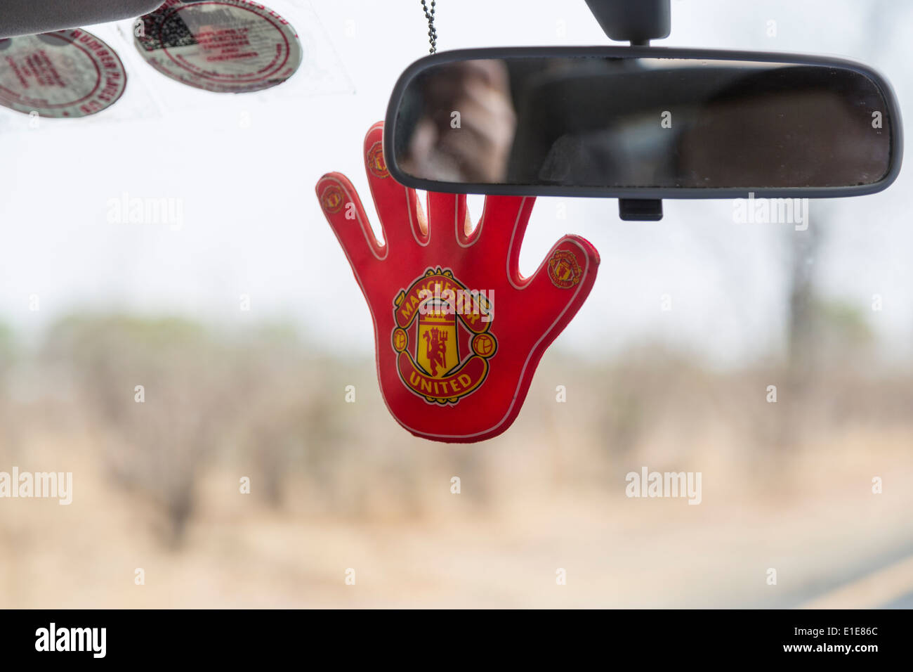 Red glove hung from the front mirror in taxi in Livingstone, Zambia, supporting Manchester United Stock Photo