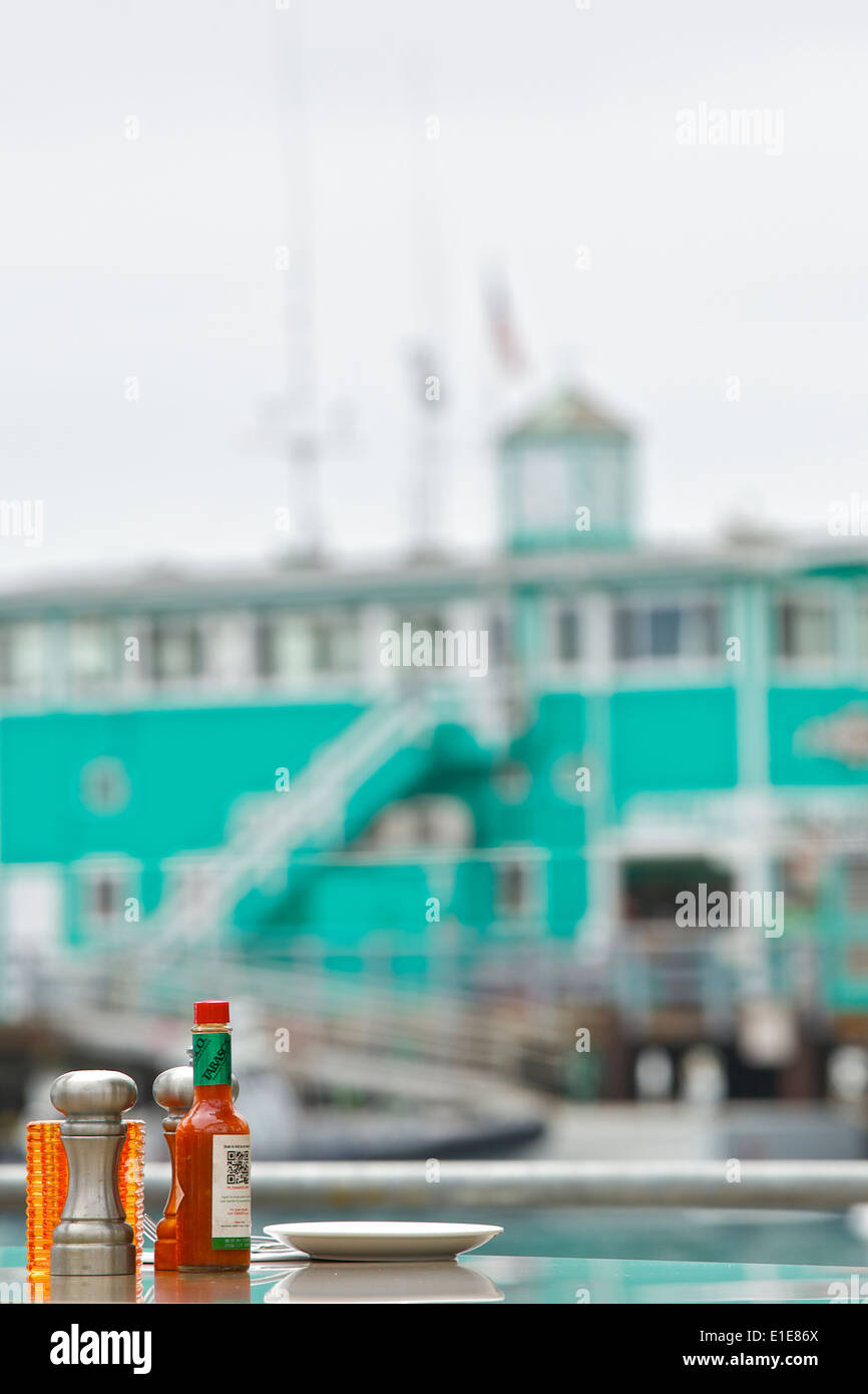 Tabasco Sauce, Salt And Pepper On A Table In A Restautant With The Green Pleasure Pier In Background, Avalon, Catalina Island, California. Stock Photo
