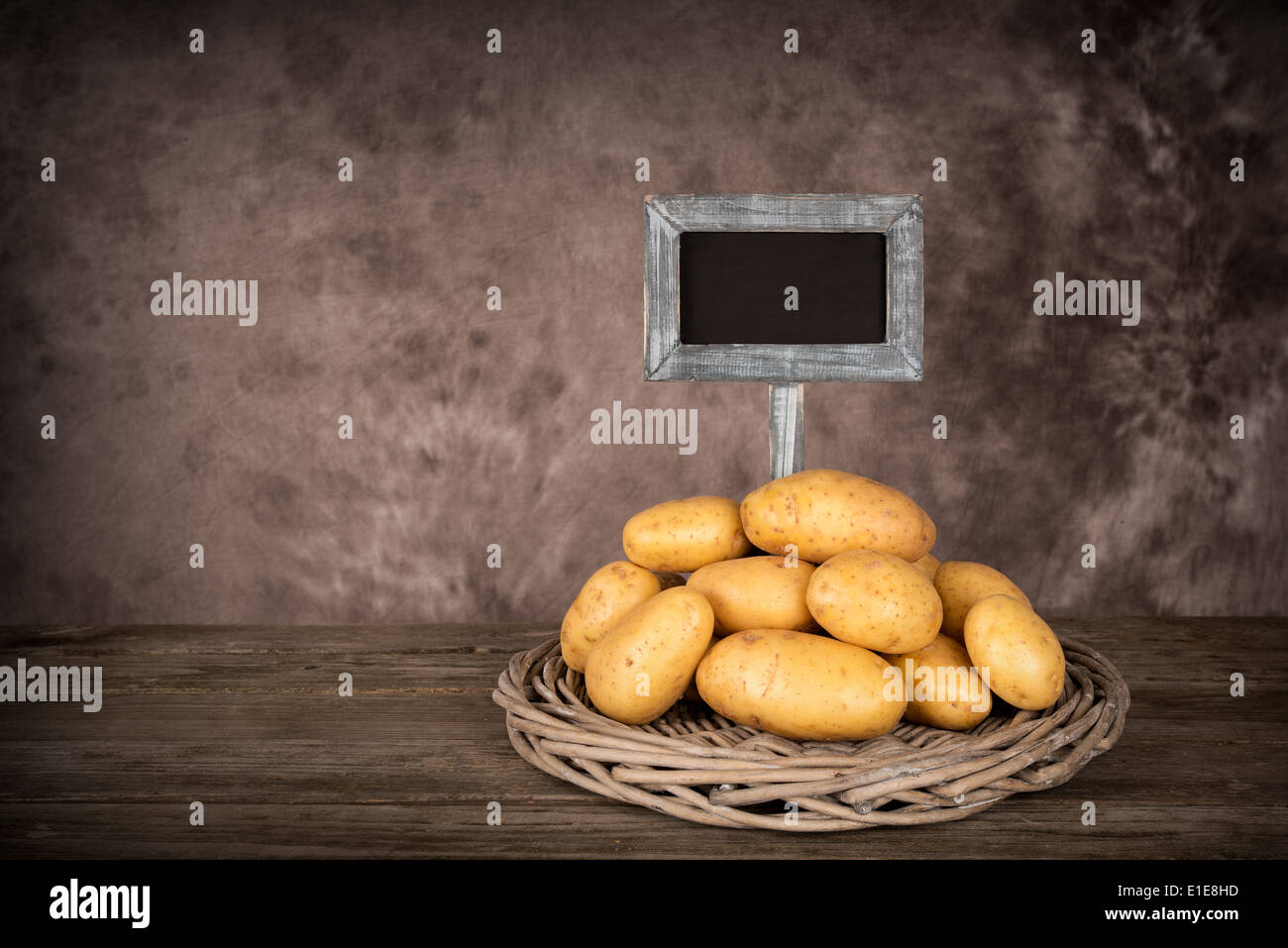 Potatoes on a table with blank price-board - isolated on white Stock Photo