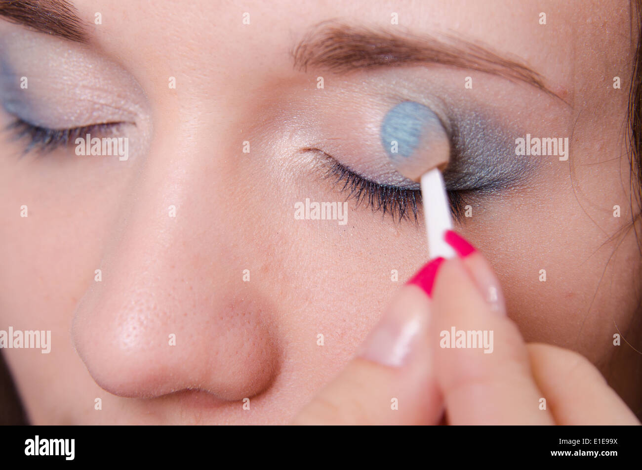 Makeup artist paints the eyelids of a beautiful young girl in the