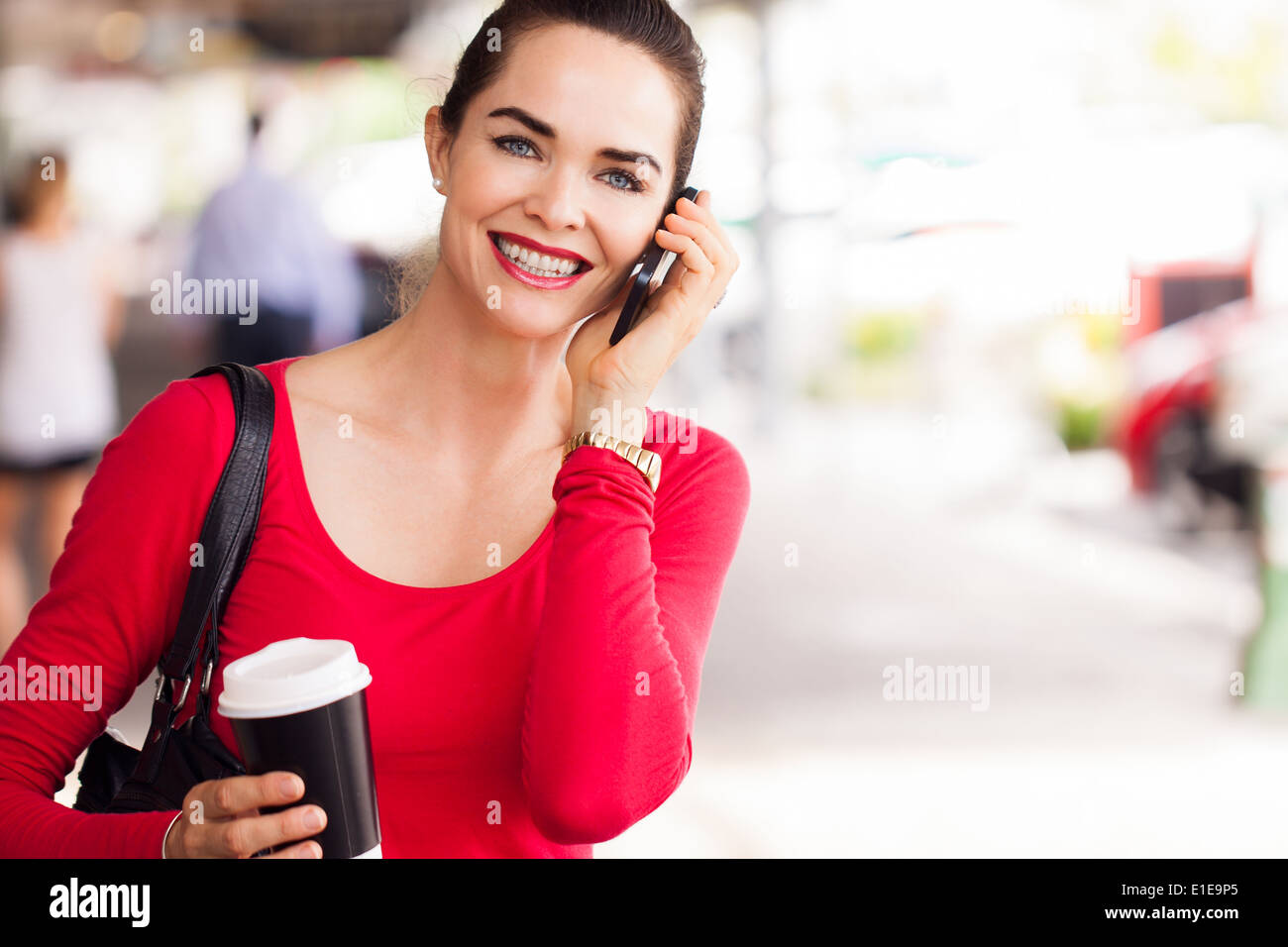 A beautiful woman out shopping holding a cup of coffee and talking on the phone. Stock Photo