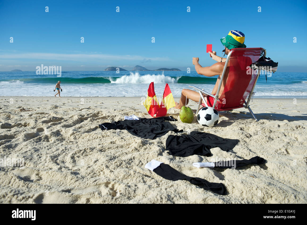 Soccer football referee holding up red card blowing whistle from a beach chair Stock Photo
