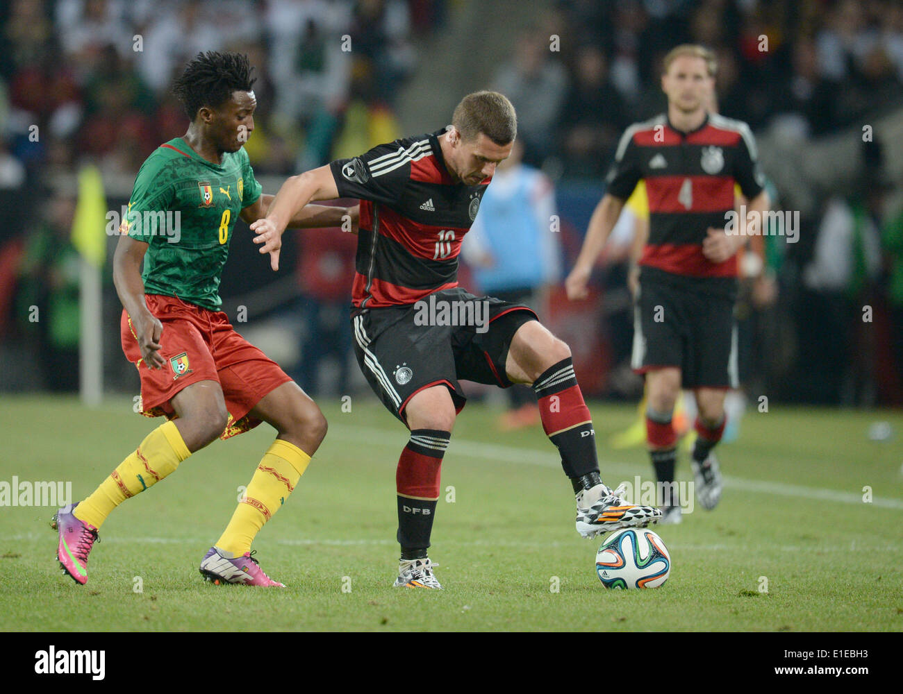 Moenchengladbach, Germany. 01st June, 2014. Germany's Lukas Podolski in action against Cameroon's Benjamin Moukandjo (R) during the friendly soccer match between Germany and Cameroon at the Borussia Park stadium in Moenchengladbach, Germany, 01 June 2014. Photo: Bernd Thissen/dpa/Alamy Live News Stock Photo