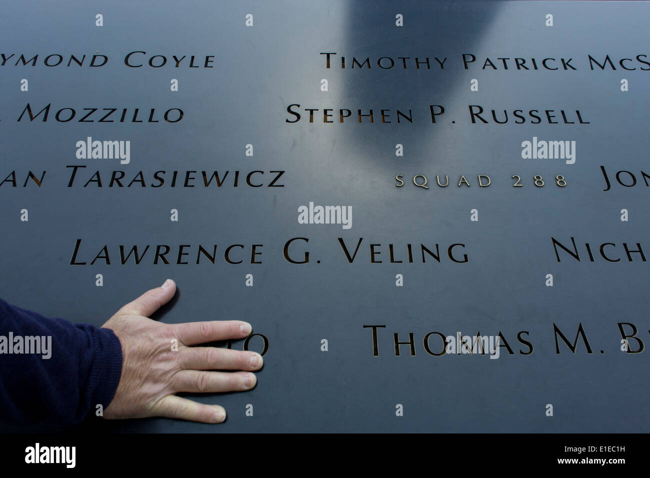 Detail of visitor's hand and names of victims at the 9/11 Memorial in New York, killed at the locations of terrorist attacks on September 11th 2001. The National September 11 Memorial is a tribute of remembrance and honor to the nearly 3,000 people killed in the terror attacks of September 11, 2001 at the World Trade Center site, near Shanksville, Pa., and at the Pentagon, as well as the six people killed in the World Trade Center bombing in February 1993. Stock Photo