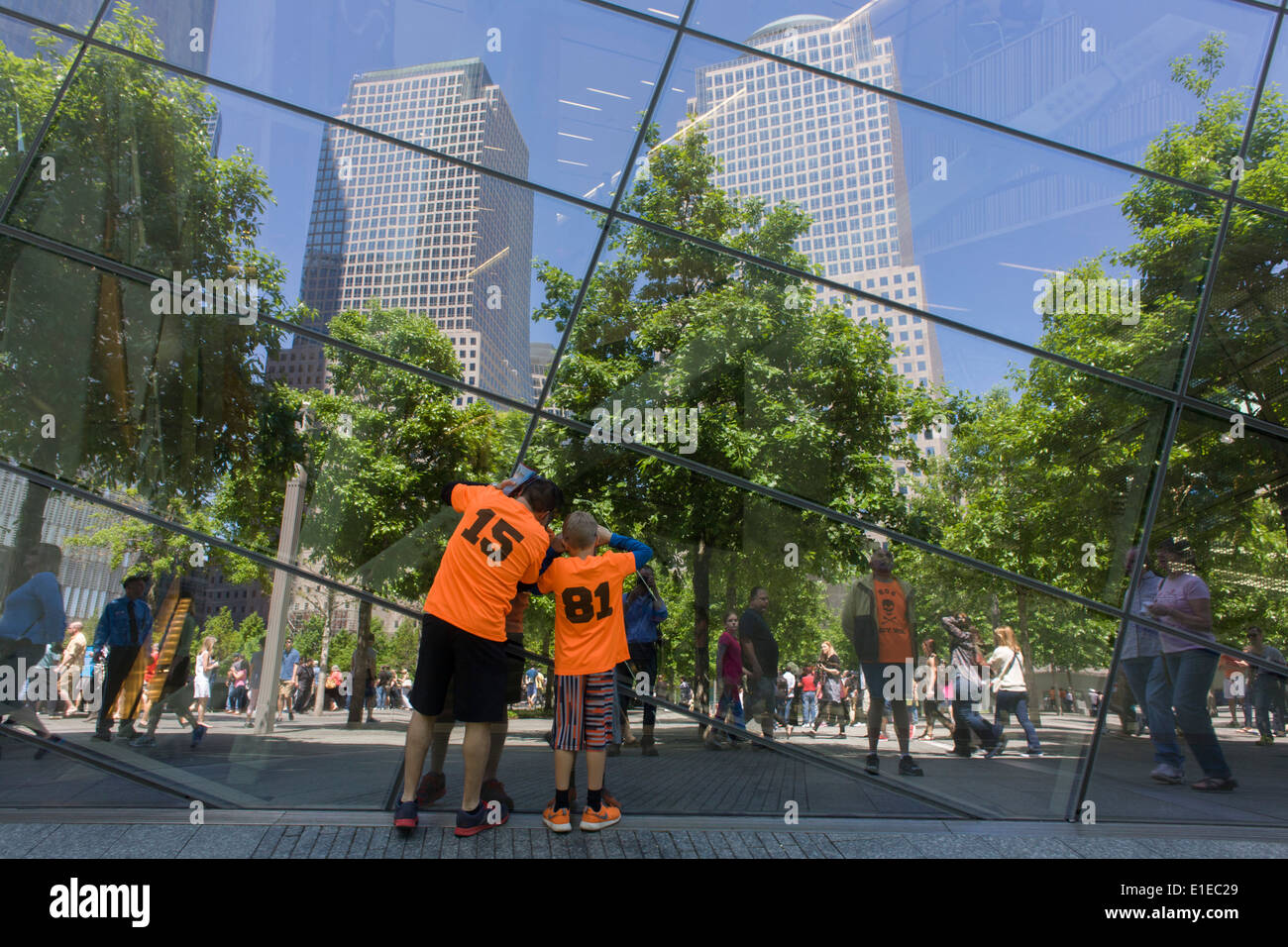 Visitors wearing identical shirts peer into plate glass window at the 9/11 Memorial in New York, killed at the locations of terrorist attacks on September 11th 2001. The National September 11 Memorial is a tribute of remembrance and honor to the nearly 3,000 people killed in the terror attacks of September 11, 2001 at the World Trade Center site, near Shanksville, Pa., and at the Pentagon, as well as the six people killed in the World Trade Center bombing in February 1993. Stock Photo