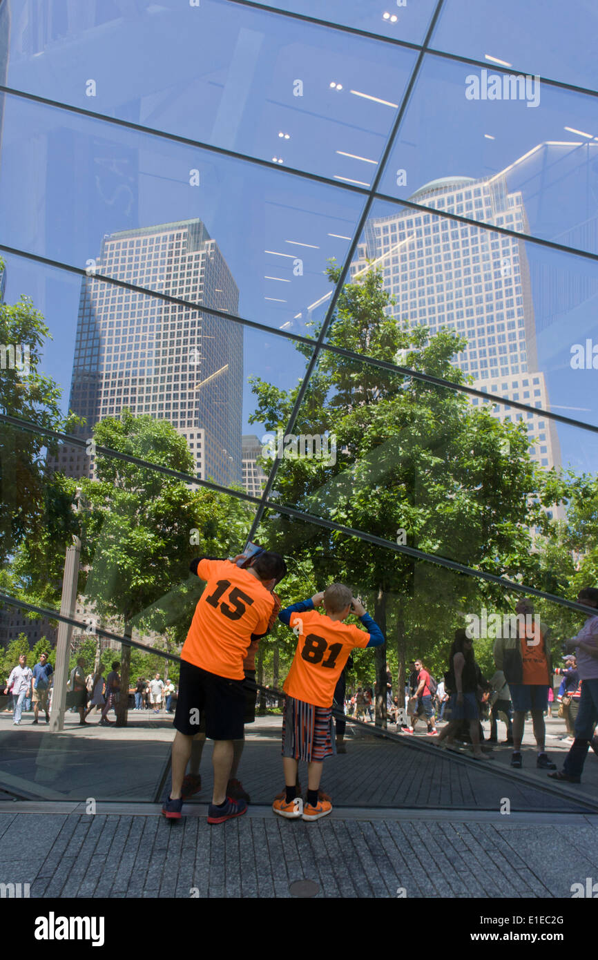 Visitors wearing identical shirts peer into plate glass window at the 9/11 Memorial in New York, killed at the locations of terrorist attacks on September 11th 2001. The National September 11 Memorial is a tribute of remembrance and honor to the nearly 3,000 people killed in the terror attacks of September 11, 2001 at the World Trade Center site, near Shanksville, Pa., and at the Pentagon, as well as the six people killed in the World Trade Center bombing in February 1993. Stock Photo