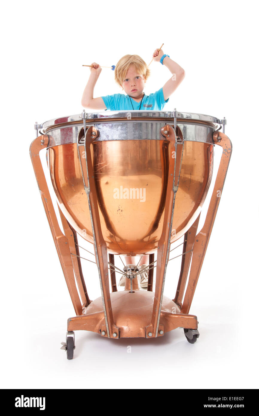 young boy playing kettle drum against white background in studio Stock