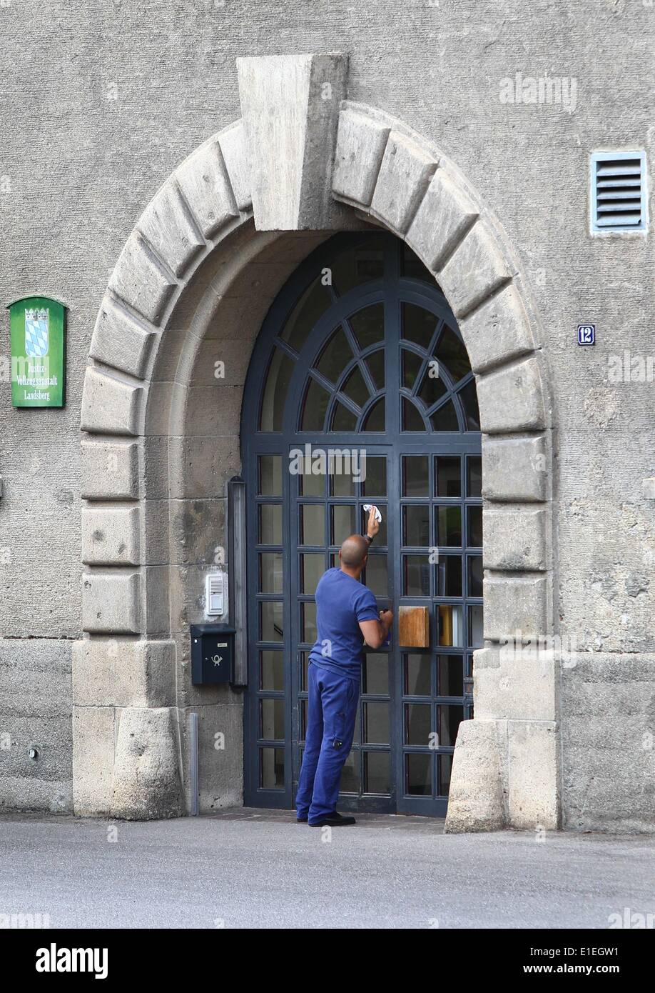 A man cleans the windows of the entrance door of the prison in Landsberg am Lech, Germany, 02 June 2014.  According to media reports on 02 June 2014, Hoeness, who was sentenced to three and half years in jail after being found guilty of evading taxes estimated at 27.2 million euros (38 million dollars) by a court in Munich, is on his way to prison in Landsberg am Lech. Photo: KARL-JOSEF HILDENBRAND/dpa Stock Photo