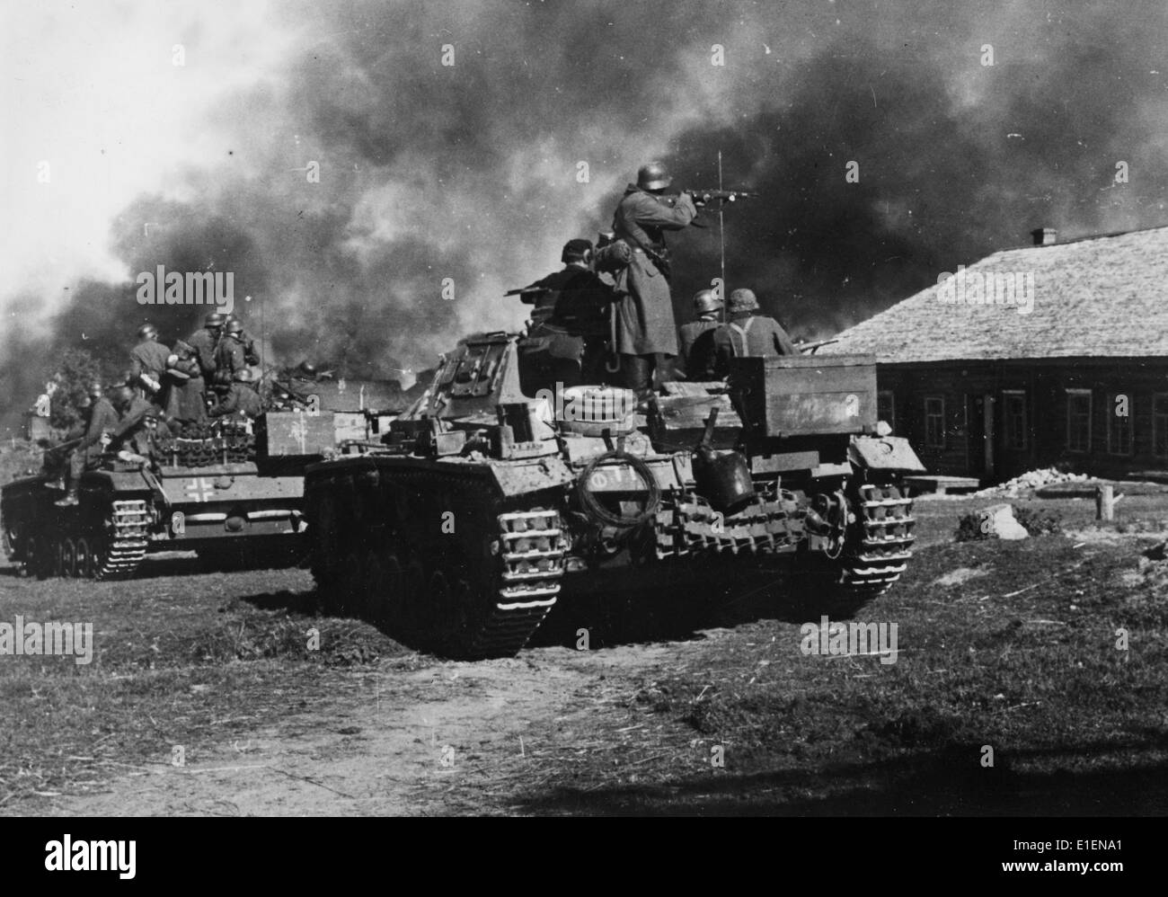 German tanks advance against Soviet settlements in October 1941. The original text from a Nazi news report on the back of the picture reads: 'The advance party at battle. The tanks of an advance party comes up against a resistance nest. The enemy' defence was tough. House after house, in which the enemy entrenched himself, was set alight. Thick clouds of smoke rose above the battle ground. The tanks pushed forward slowly, with the infantry advanced behind weapon at the ready.' Fotoarchiv für Zeitgeschichtee - NO WIRE SERVICE Stock Photo
