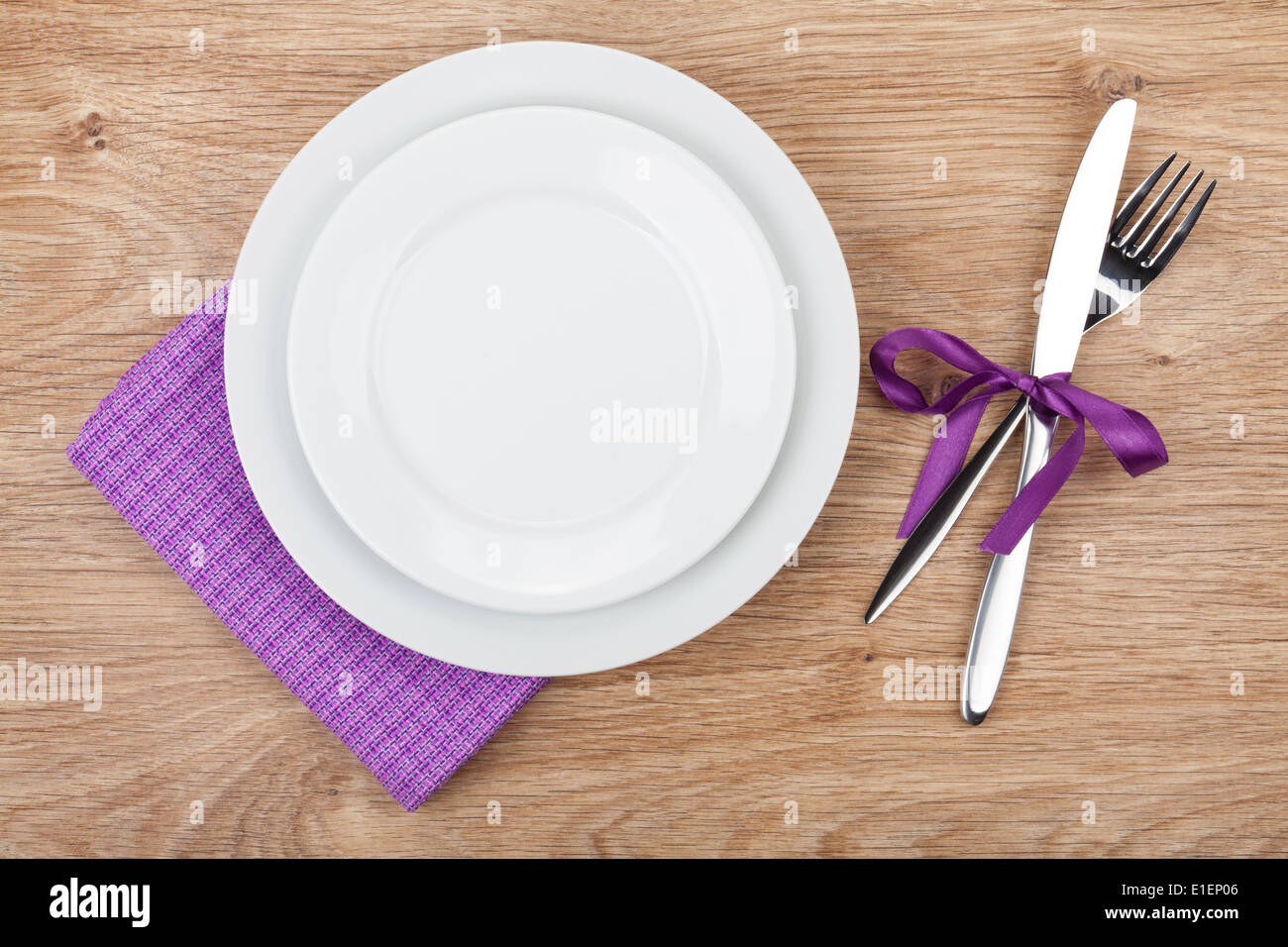 Fork with knife, blank plates and napkin. On wooden table background Stock Photo
