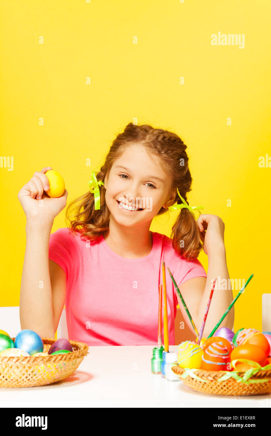 Smiling girl sits at the table with Easter eggs Stock Photo