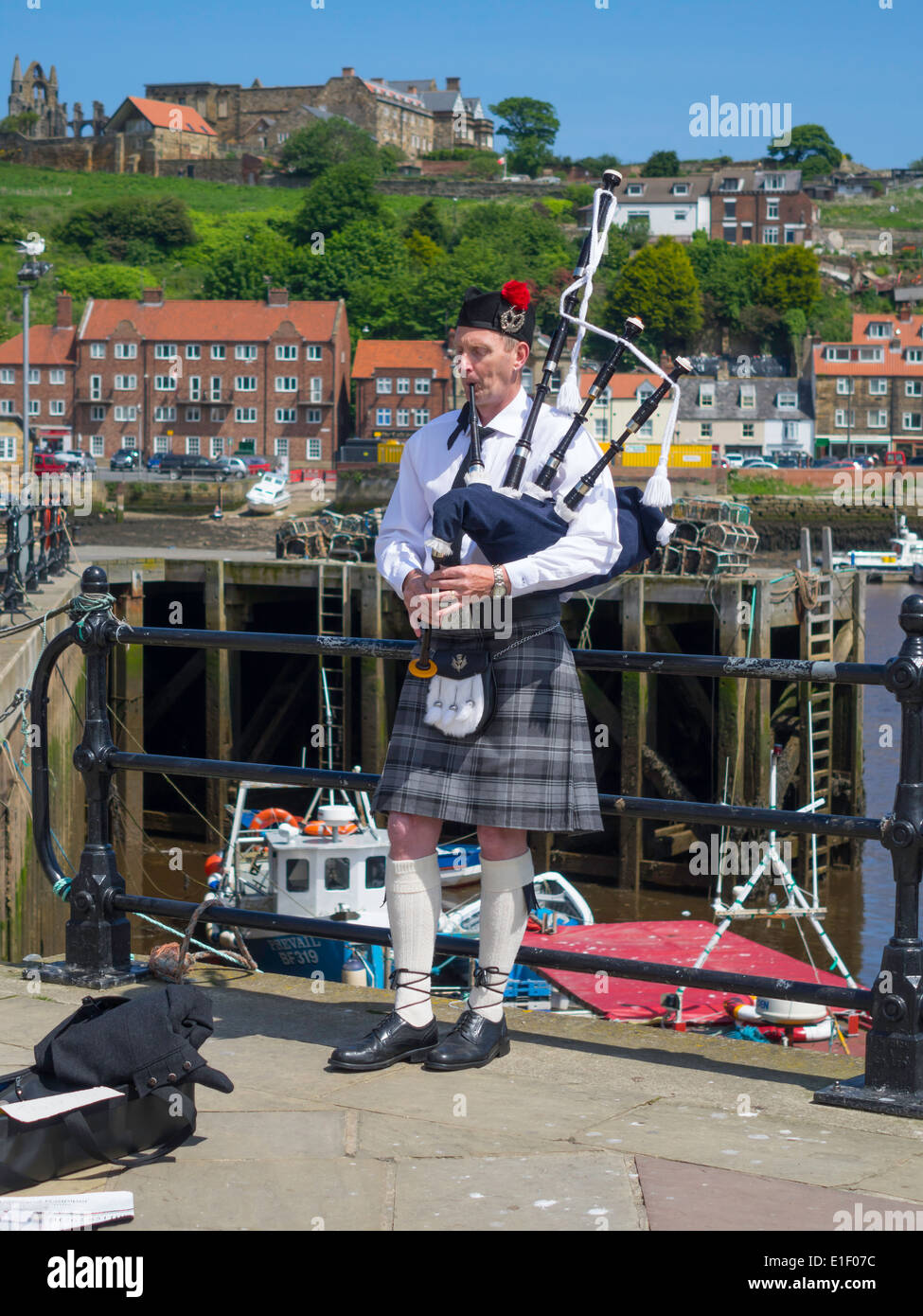 Busker man playing Scottish Bagpipes by Whitby Harbour on a warm spring day Stock Photo