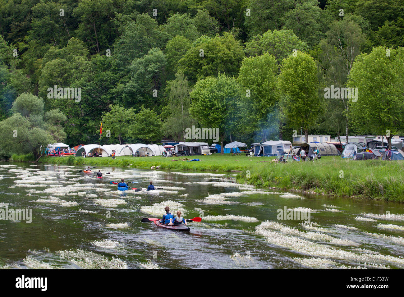 Tourists in canoes and kayaks passing a camping along the Semois river in the neighborhood of Mortehan in the Ardennes, Belgium Stock Photo