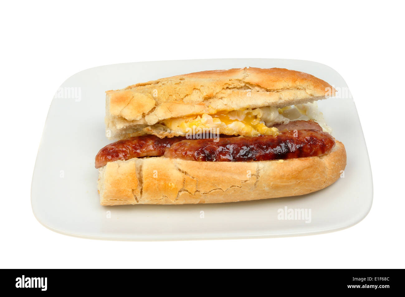 Fried egg and sausage baguette on a plate isolated against white Stock
