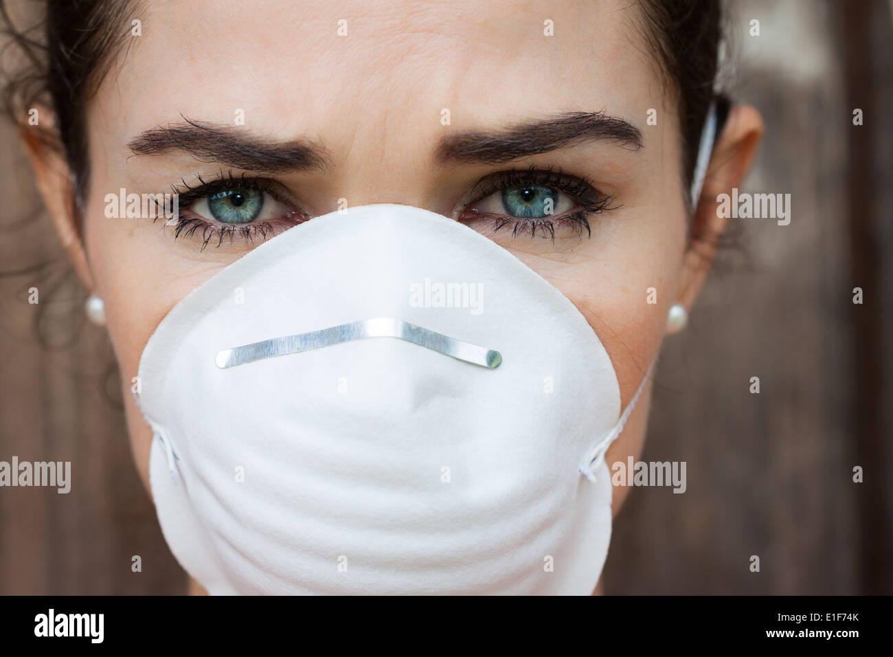 Close-up of an unhappy woman wearing a face mask to deal with virus or pollution. Stock Photo