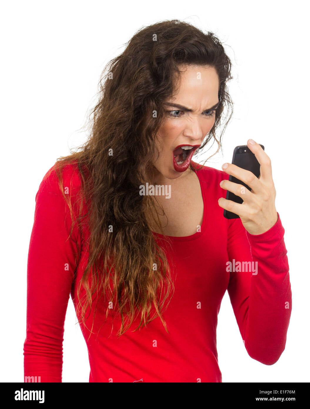 A very angry, annoyed and frustrated woman screaming at her phone in rage. Isolated on white. Stock Photo