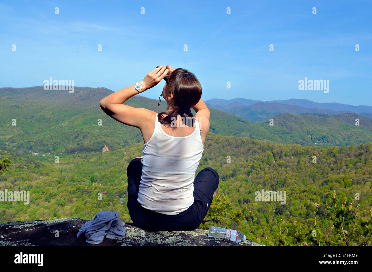 A woman hiker on an overlook looking for birds. Stock Photo
