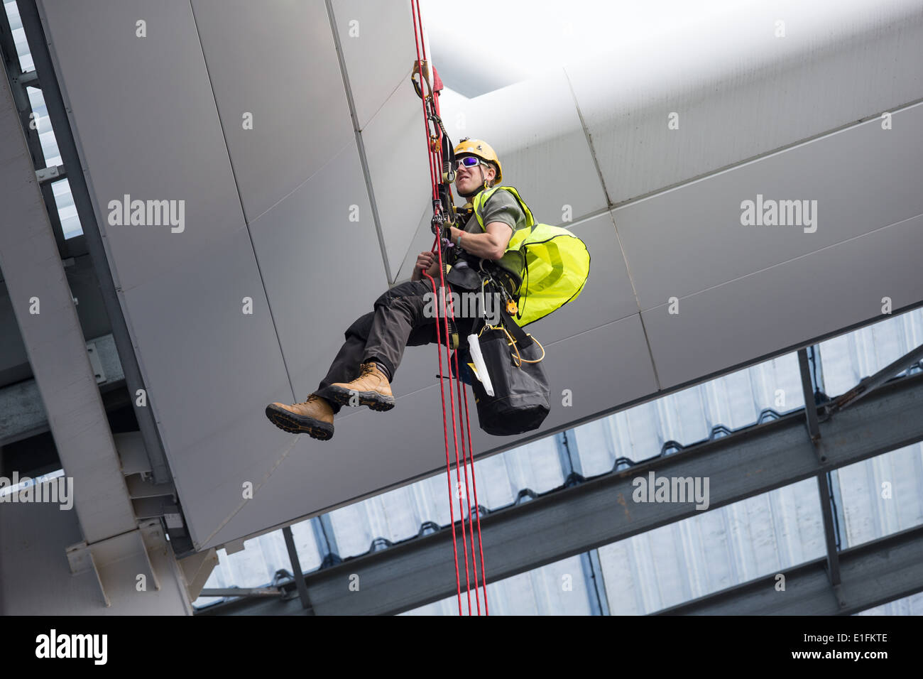 Tradesman workman cleaning a roof using ropes and pulleys abseil mountaineering climbing equipment Stock Photo